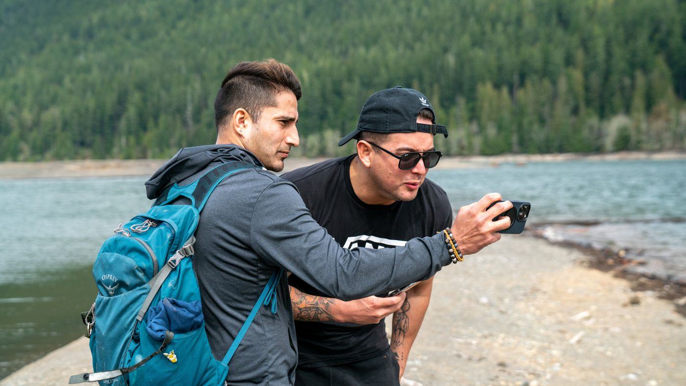 Two backpackers checking a phone together at a viewpoint