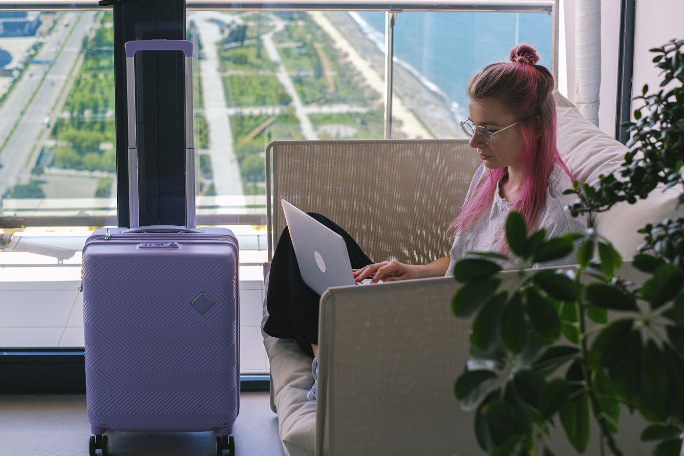Eine Person arbeitet am Schreibtisch eines Hotelzimmers mit Laptop und Kaffee