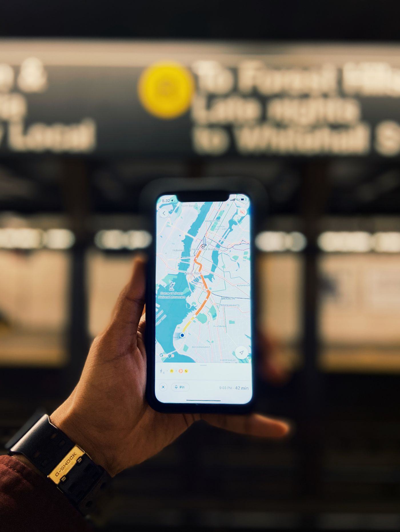 地下鉄のホームで、路線図を表示したスマートフォンを片手で持っている様子
